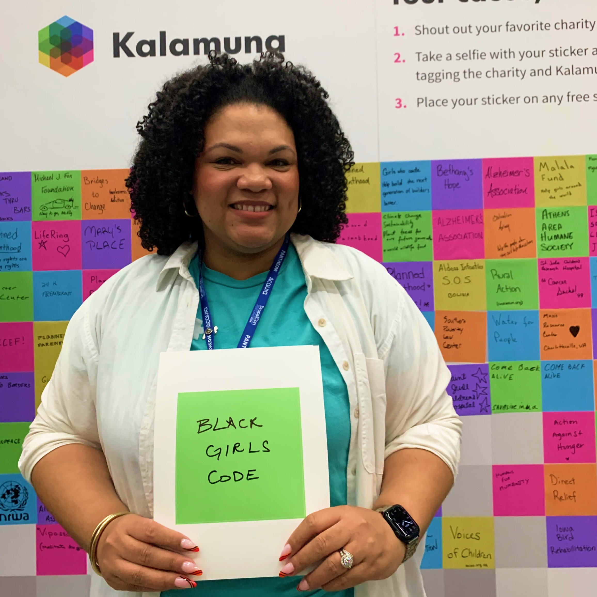 Britany Acre holds a green square sticker with "Black Girls Code" written on it.