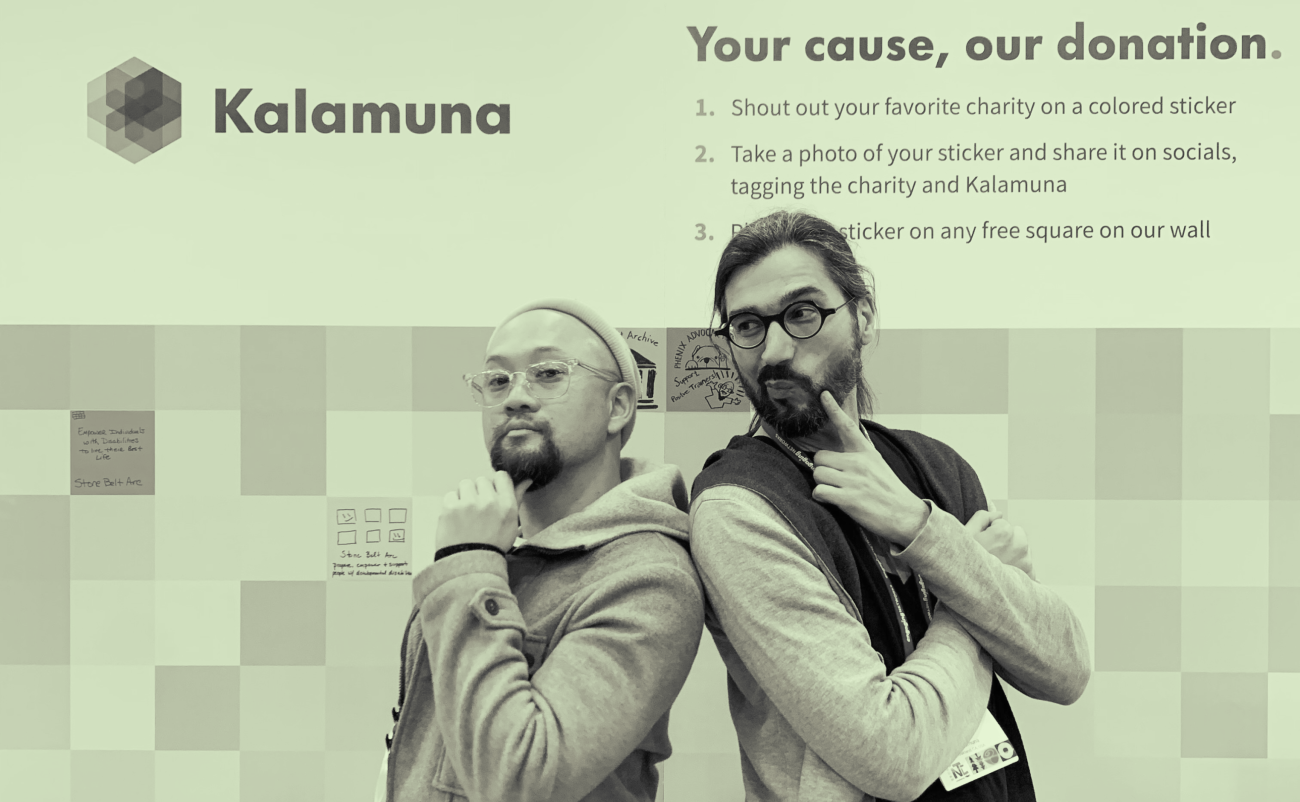 Ken Lo, a shorter Asian man wearing glasses, sweater and a beanie, and Andrew Mallis, tall bearded Persian man with a pony tail, back-to-back with arms crossed in front of our Kalamuna banner that says 'Your cause, our donation."